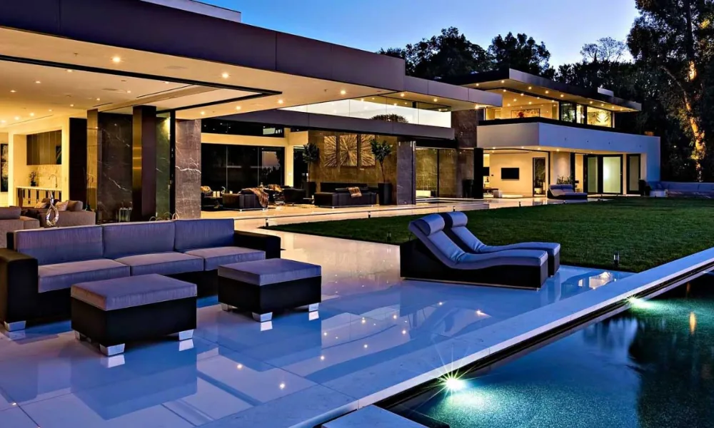 Villa contemporánea iluminada de noche con piscina y salón abierto al jardín