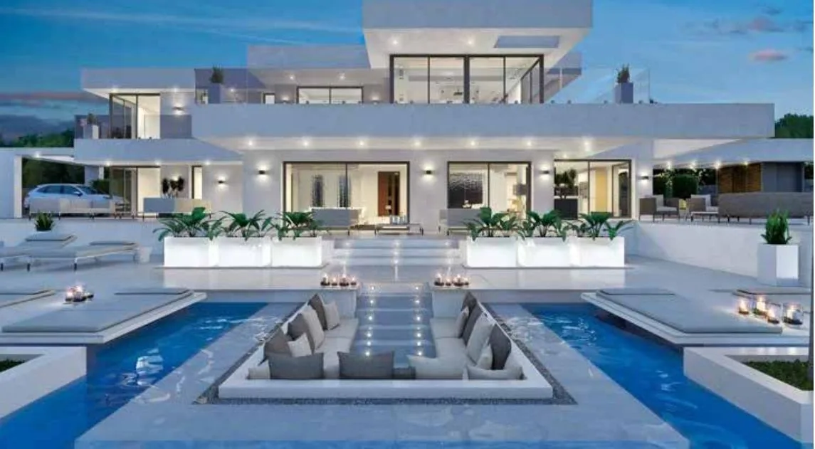 Villa blanca de líneas rectas con piscina iluminada al anochecer